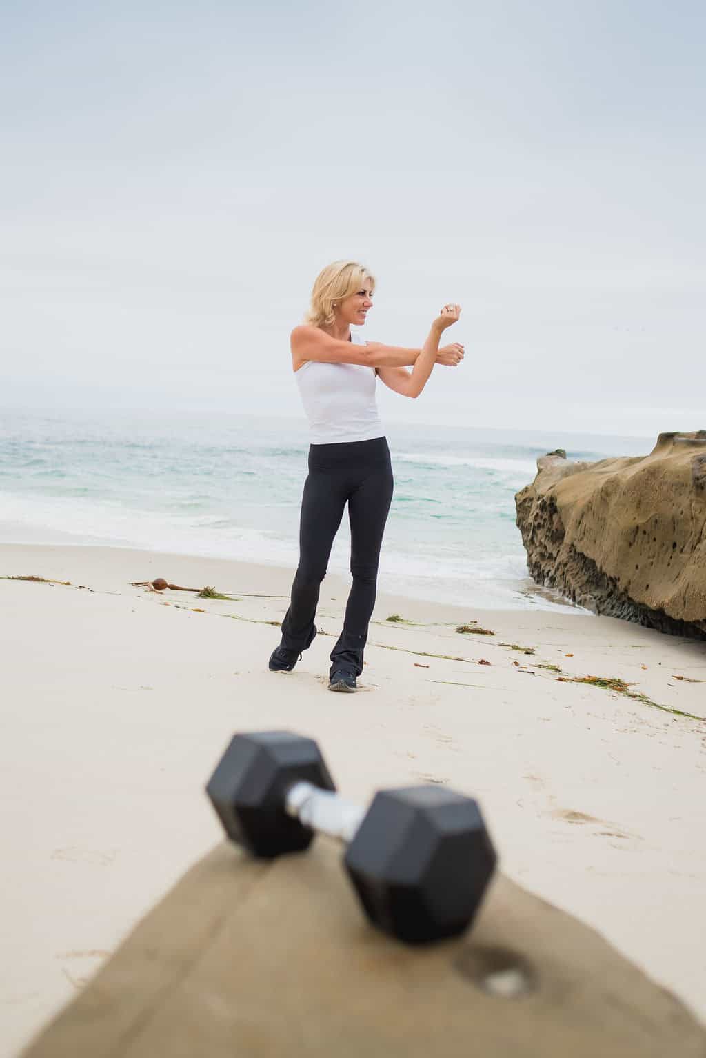 Rose Martin stretching her arms on the beach near the water